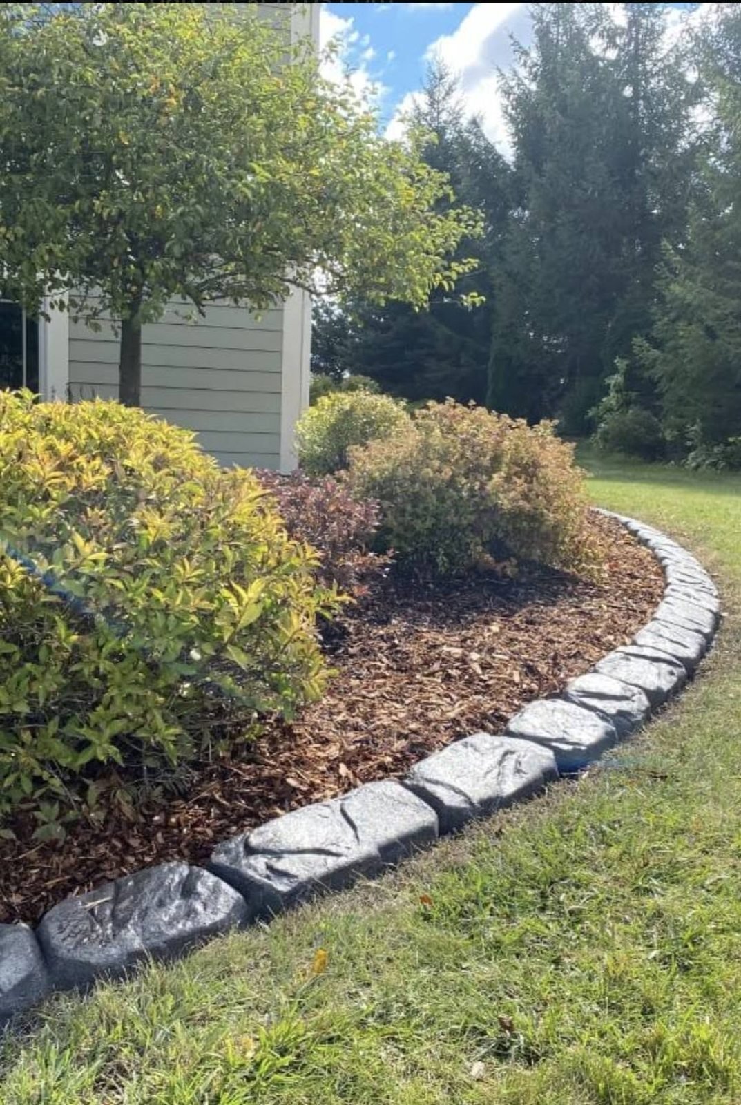 Rock-face concrete landscape curbing along a mulch bed